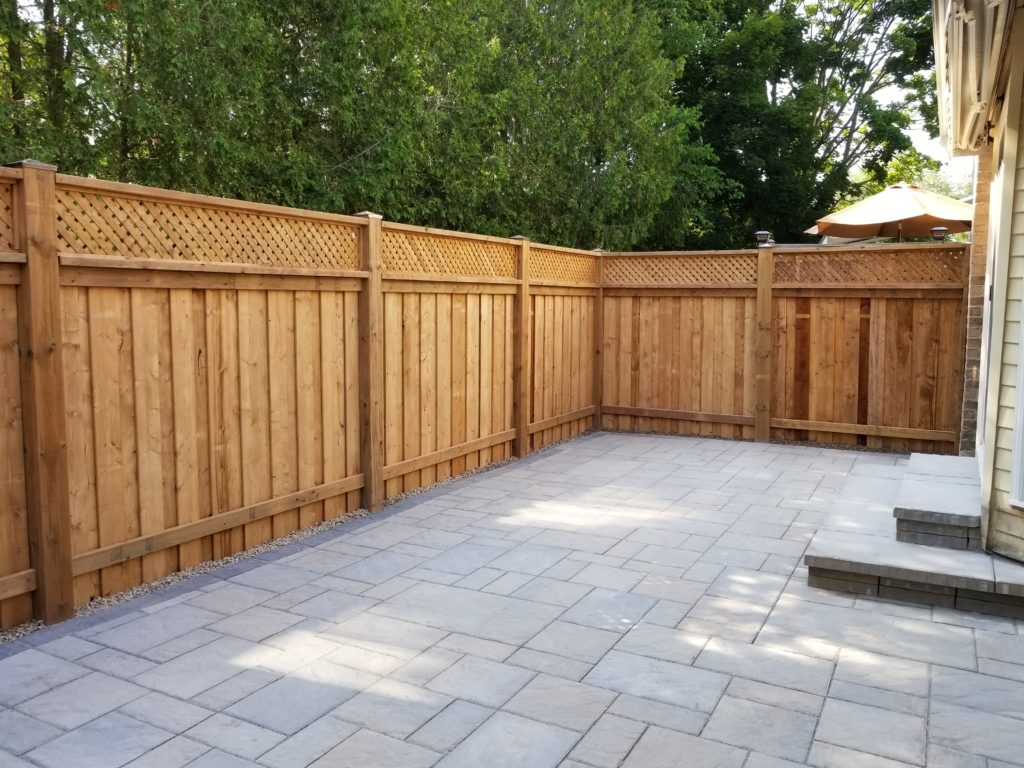 Backyard fence on an interlock garden patio.