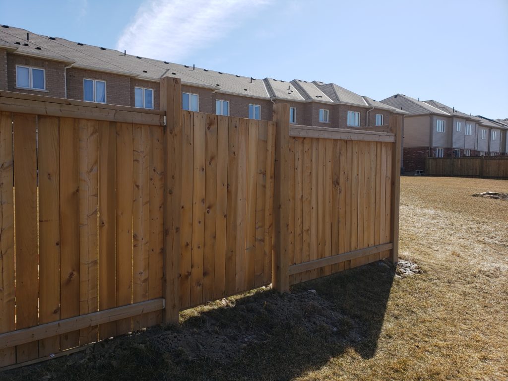 Backyard fence in a wide field.